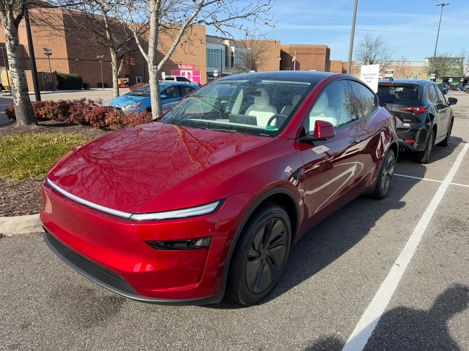 A red Tesla Model Y sitting in a parking lot.